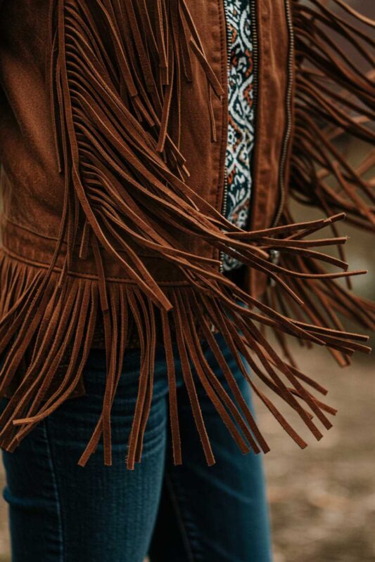 Close-up of leather fringe detail in motion showing texture and movement for Moto Boho style.