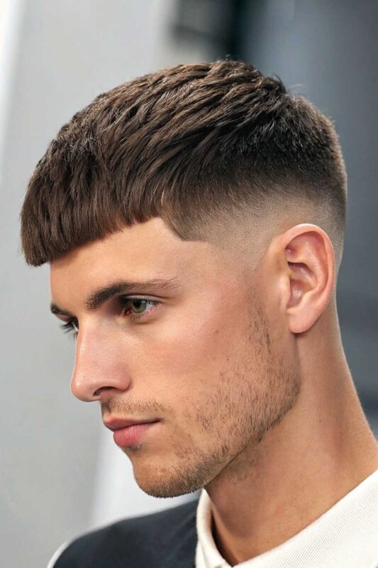 Young man with a French crop hairstyle featuring textured top and blunt fringe, perfect for summer.