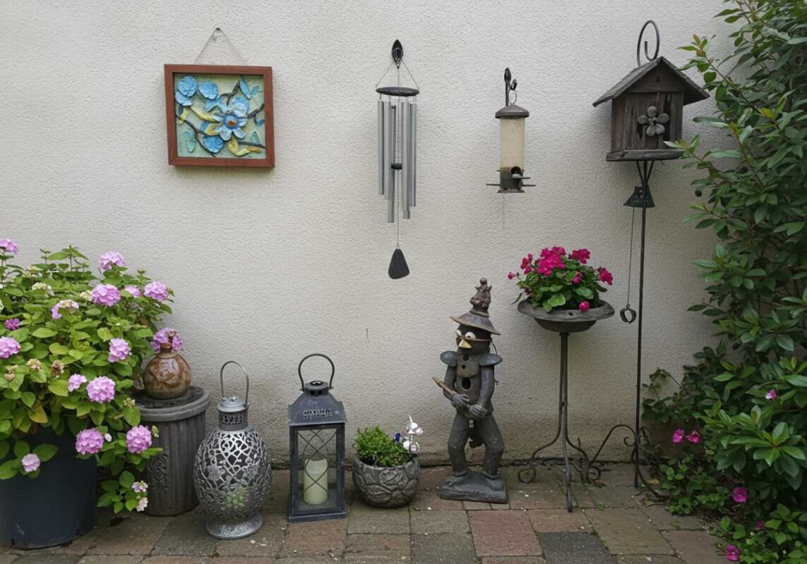 Close-up of outdoor decor details including artwork, garden sculpture, lanterns, and bird feeder.