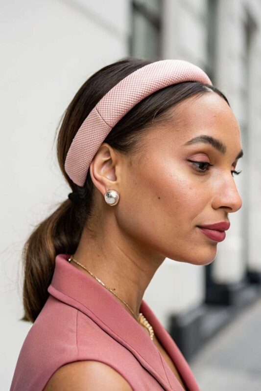 A young woman with a headband and a low ponytail hairstyle.