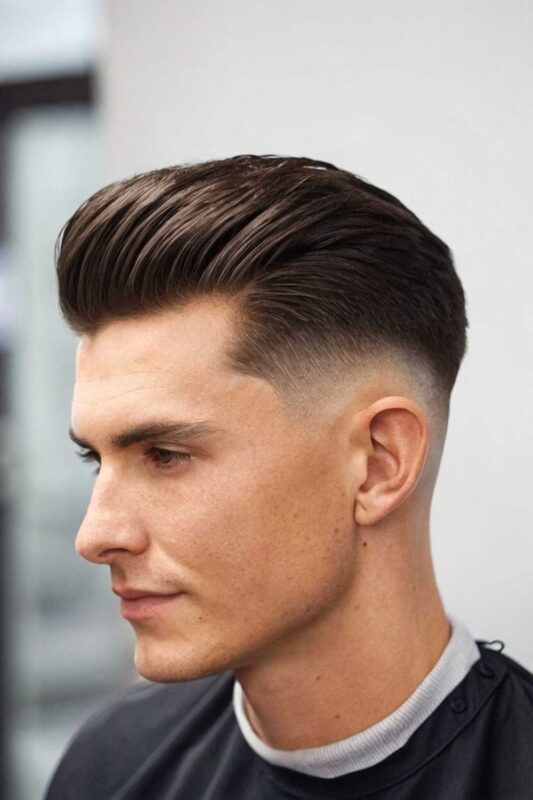 Man with a slick fade, featuring faded sides and styled length on top for versatile looks.