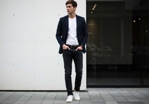 Man wearing navy blazer with white t-shirt and jeans demonstrating casual professional style.
