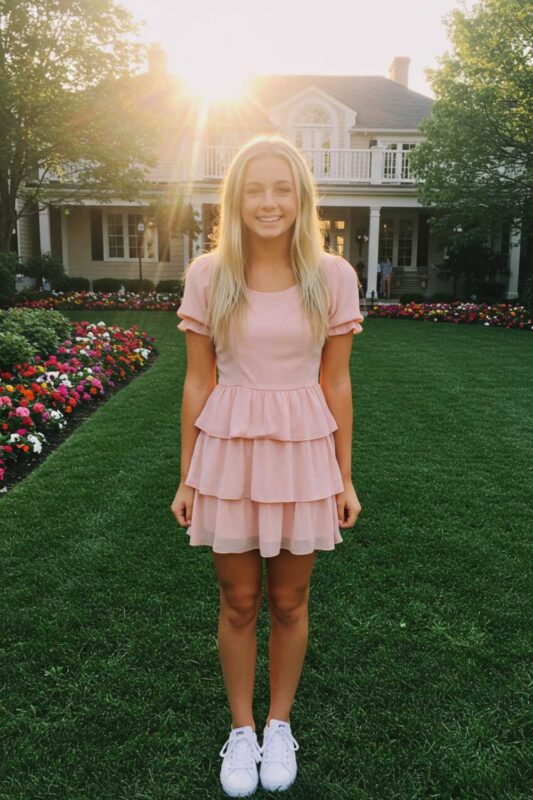 Teen girl in pink ruffled mini dress playful summer outfit.