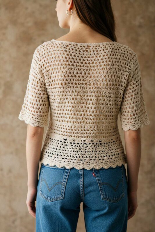 Lightweight crochet top with intricate texture styled with high-waisted jeans.