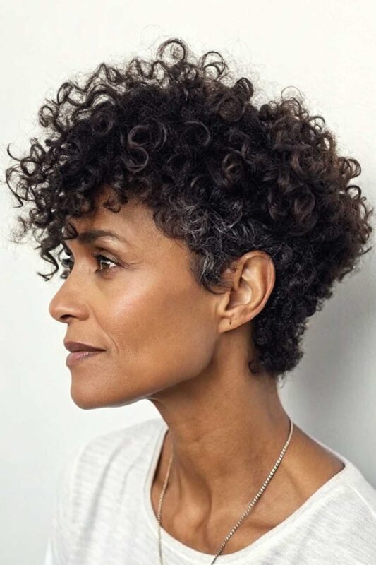 A mature woman with a curly cut hairstyle.