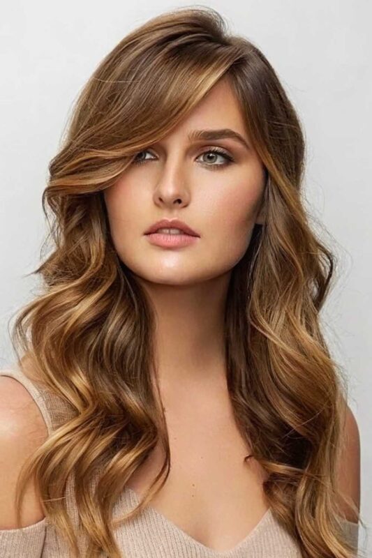 Woman with long wavy hair and elegant side-swept bangs.