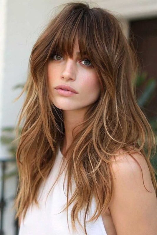 Woman with long textured hair and shaggy bangs.
